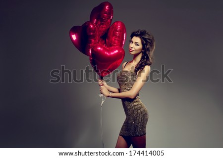 Beautiful brunette young woman in golden dress with a heart-shaped balloons. Valentine\'s day