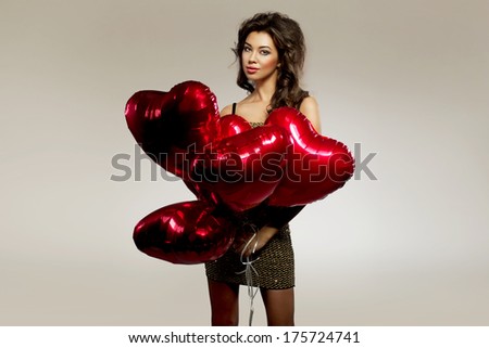 Beautiful brunette young woman in golden dress with a heart-shaped balloons. Valentine\'s day