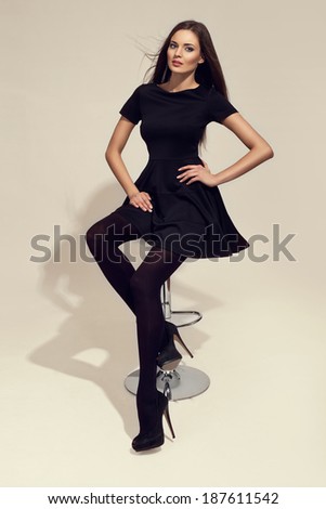 Sexy elegant woman sitting on a chair, long legs, black thighs and high heels