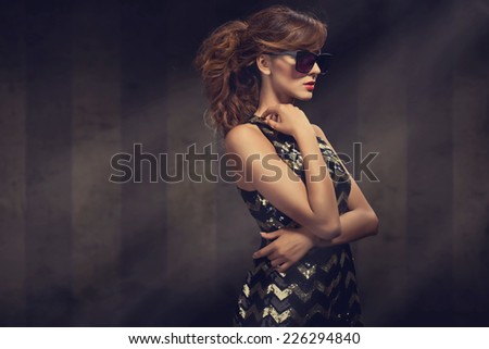 beautiful young woman in elegant glitter dress and big sunglasses. Fashion photo