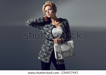 Beautiful elegant woman in stylish cardigan, high heels holding handbag. Fashion shot