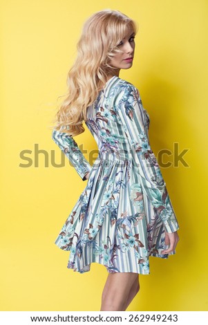 beautiful young blonde woman in nice spring dress, posing on yellow background in studio. Fashion photo