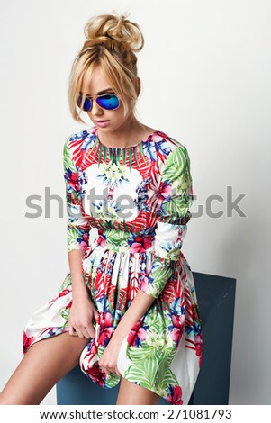 beautiful young blonde woman in nice spring dress, posing in studio, sunglasses. Fashion photo
