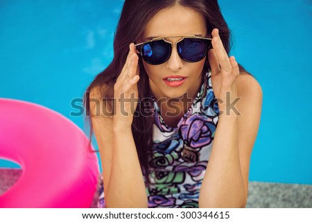 fashion photo of sexy beautiful girl with brunette in nice clothes relaxing beside a swimming pool