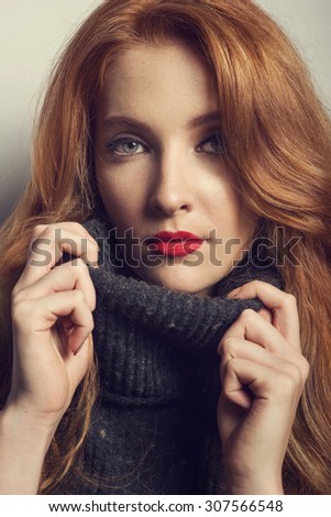Beautiful young red haired woman with nice make up in autumn color, red lips, turtleneck. Fashion studio photo