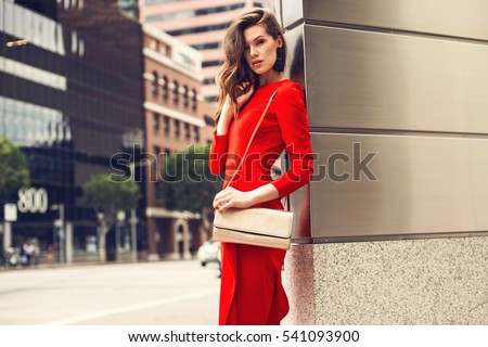 https://image.shutterstock.com/display_pic_with_logo/1125836/541093900/stock-photo-beautiful-brunette-young-woman-wearing-red-dress-golden-purse-walking-on-the-street-fashion-photo-541093900.jpg