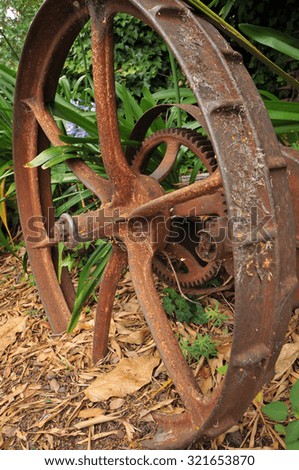 Rusty wheel of an old agricultural machine in grass.