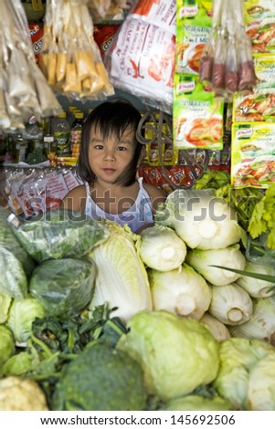 PHILIPPINES - DECEMBER 22, 2011 - Unidentified child helps her parents sell vegetables at the local market on December 22, 2011 at Philippines. Millions of Filipino children work to help their family.