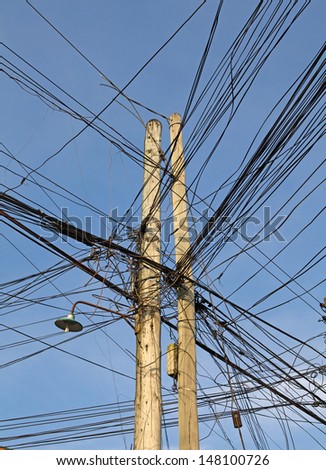 Tangled, unsafe and dangerous telephone and electric wires on a telephone pole in a third world country.