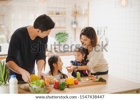 Young Asian love family are preparing the breakfast, sandwich vegetable on table in the kitchen which Excited smiling and felling happy. parent teach daughter to cooking food on the day at home. 