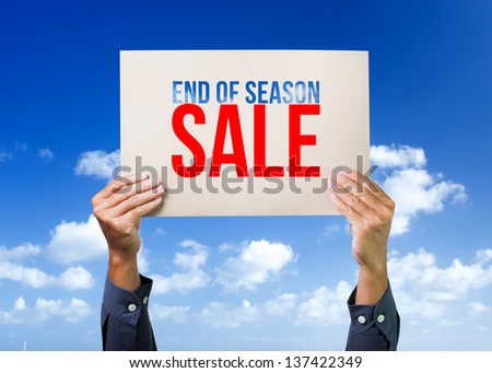 Two hands holding brown cardboard with end of season sale overhead on blue sky background