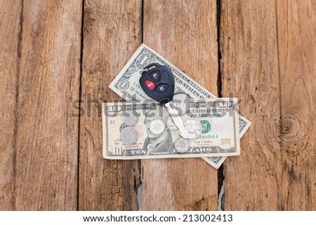 Car remote key with dollar money on wood background
