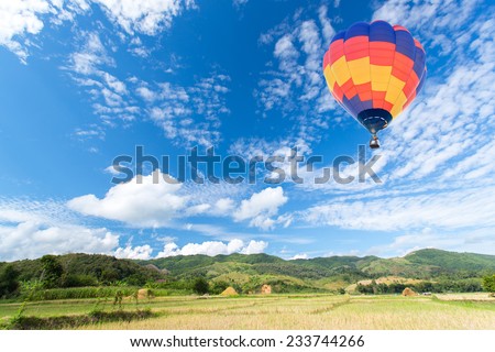 Hot air balloon over rice fields with mountain background