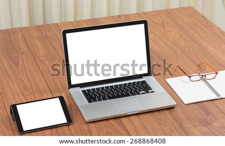 Blank screen laptop computer with office accessories on wooden table