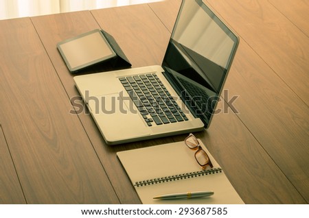 Laptop computer and office accessories on wooden table with vintage color effect