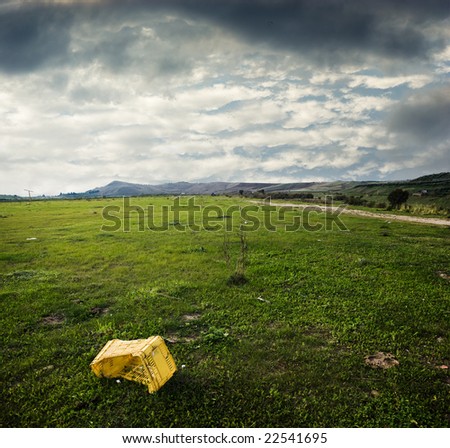yellow plastic box abandoned in desolate grass area