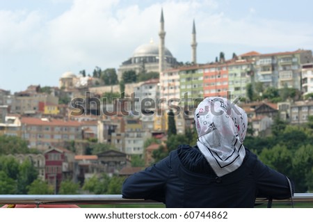 a musulman woman is wearing religious veil and is looking at a Istanbul cityscape with a mosque