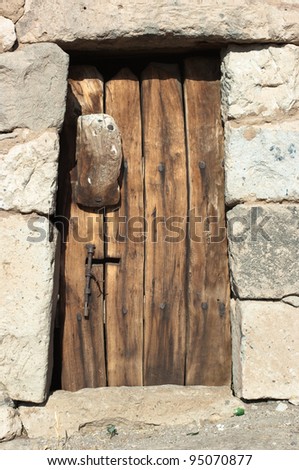 a cyclopean wall with a door made of planks of wood raw burned and nailed in Cappadocia, Turkey