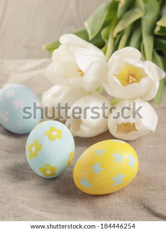 pastel color easter eggs with tulips on table, slightly toned photo
