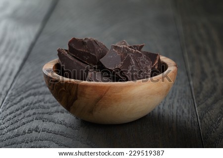 dark chocolate chunks in wooden bowl, on oak table