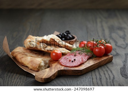 Antipasti with salami, olives, tomatoes and bread on wod table