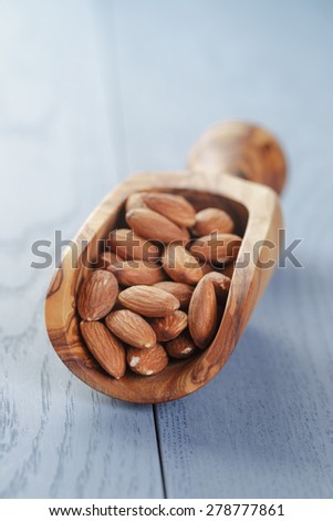 roasted almonds in measuring scoop on blue wooden table