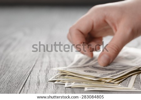 young female hands count dollar bills on wood table with copy space, closeup photo