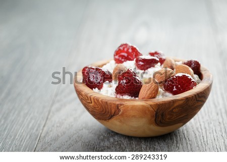 cottage cheese with preserved strawberry in wood bowl on oak table, selective focus
