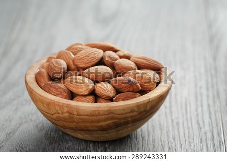 roasted almonds in bowl on gray wooden table, shallow focus
