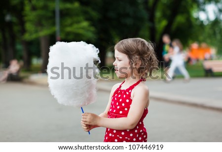 Beautiful little girl eating cotton candy in the street