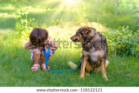 Happy little girl playing with big dog in the garden