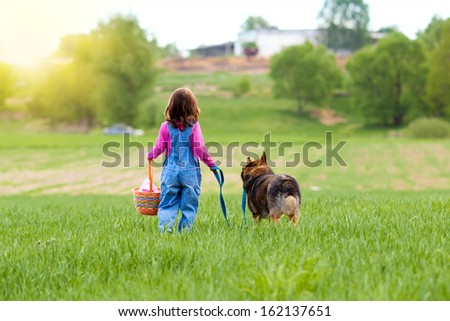Little girl with dog walking on the field to the picnic