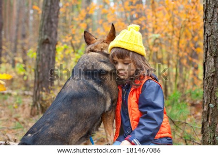 Sad little girl with big dog in the forest in autumn