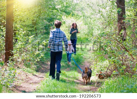 Family with dog doing morning exercises in the forest. Mom with kid blurred.
