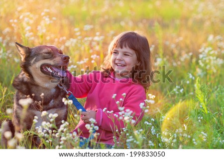 Happy little girl with big dog sitting in the lawn