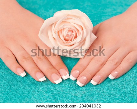 Beautiful woman\'s hands with french manicure and rose on towel
