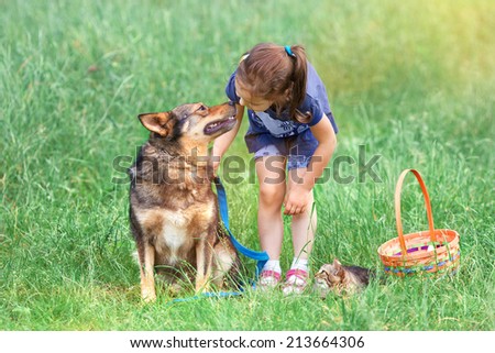 Little girl with dog and cat on picnic. Girl talking to dog