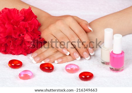Beautiful woman\'s hands with perfect french manicure on white towel decorated with flower and nail polish