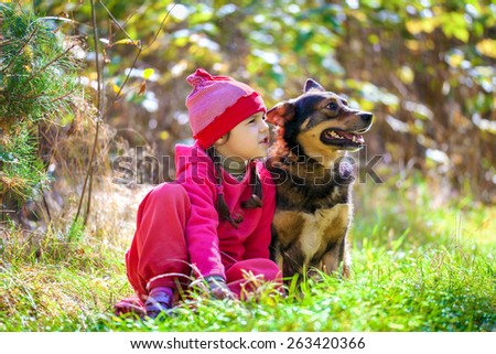 Little girl siting with dog on the lawn in the forest