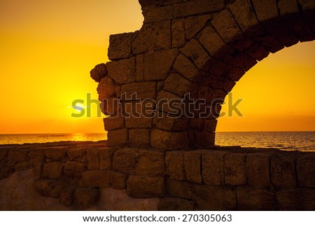 Remains of the ancient Roman aqueduct in ancient city Caesarea at sunset, Israel.