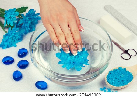 Beautiful woman\'s hand with perfect french manicure bathing in bowl of water