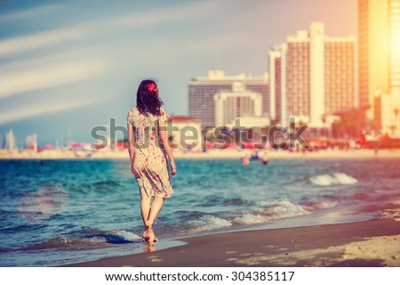 Young woman walking back to camera at sunset on the beach in Tel Aviv, Israel
