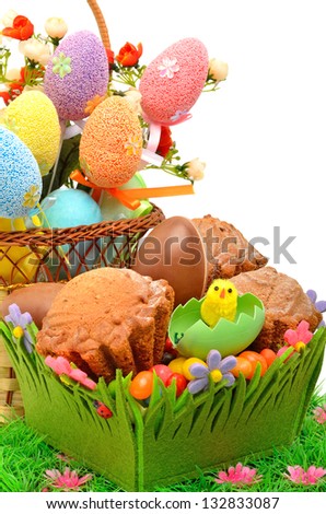 Easter eggs in the basket, chocolate eggs and muffins on the grass isolated on white