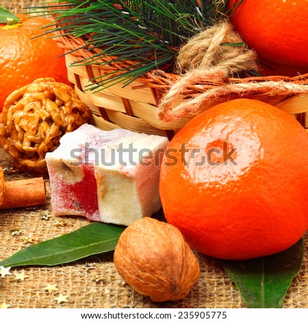 Christmas tangerines with sweet delights, walnuts, pinecone and brittle candies on christmas sacking background