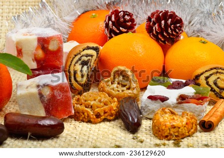 Christmas tangerines, turkish sweet; lokum, pinecone and brittle candies on christmas sacking background