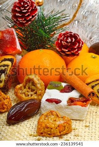 Christmas tangerines, lokum, pinecone and brittle candies on christmas sacking background