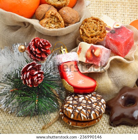 Christmas tangerines, lokum, pinecone and brittle candies on christmas sacking background