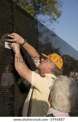 A park ranger copying a name of the Vietnam War Memorial for an elderly lady