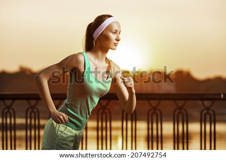 Running woman. Runner is jogging on sunrise. Female fitness model training outside in the city on a quay. Sport lifestyle.