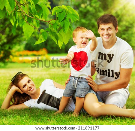 Happy young family is having fun in the green summer park outdoors on a sunny day.
